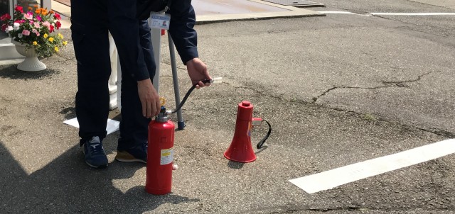 消火器を地面に置き上から体重をかける