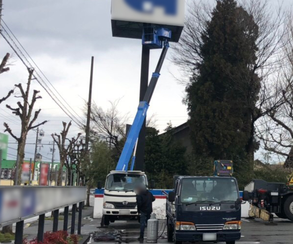 伸縮式ブームの高所作業車を使って看板を解体中