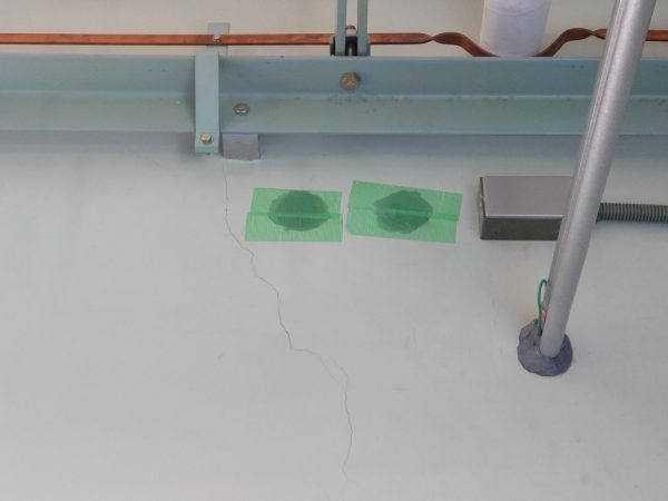壁に二つの穴があいており、緑の養生テープで防がれている